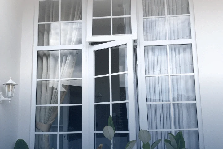 Jendela UPVC putih model casement dengan sekat kaca pada rumah tinggal