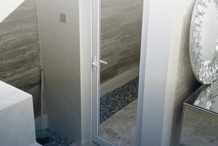 Pintu kaca UPVC putih di samping dinding batu dan cermin dekoratif